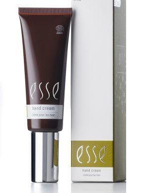 A tube of Esse Hand Cream is displayed next to its box. The brown tube, accented with a silver cap, prominently features "Esse" and "Hand Cream" in white text. The accompanying white box shares a similar design, showcasing the "Esse Hand Cream" text along with additional branding elements.