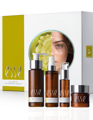 A white box labeled "20 day trial" with a circular cutout reveals part of a woman's face and a green botanical image. In front of the box are four brown skincare bottles with white labels, including a gel cleanser, hydrating cream, serum, and eye cream, all branded with "Esse" from the Esse Oily / Combination / Normal Trial / Travel Set.