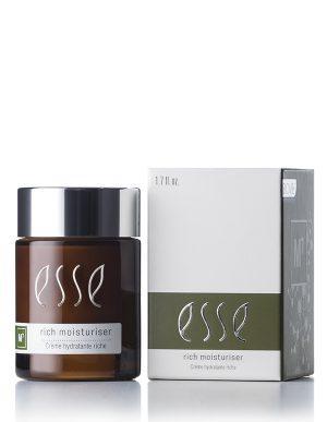 A 50ml brown glass jar of Esse Rich Moisturiser with a silver cap is placed next to its corresponding box. Both the jar's label and the box display the brand name "Esse" along with product information in white and green text.